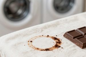 Свежее шоколадное пятно на светлой хлопковой ткани